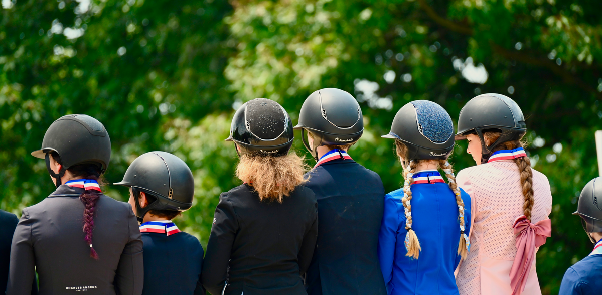 Young riders lined up with ribbons at a horse show