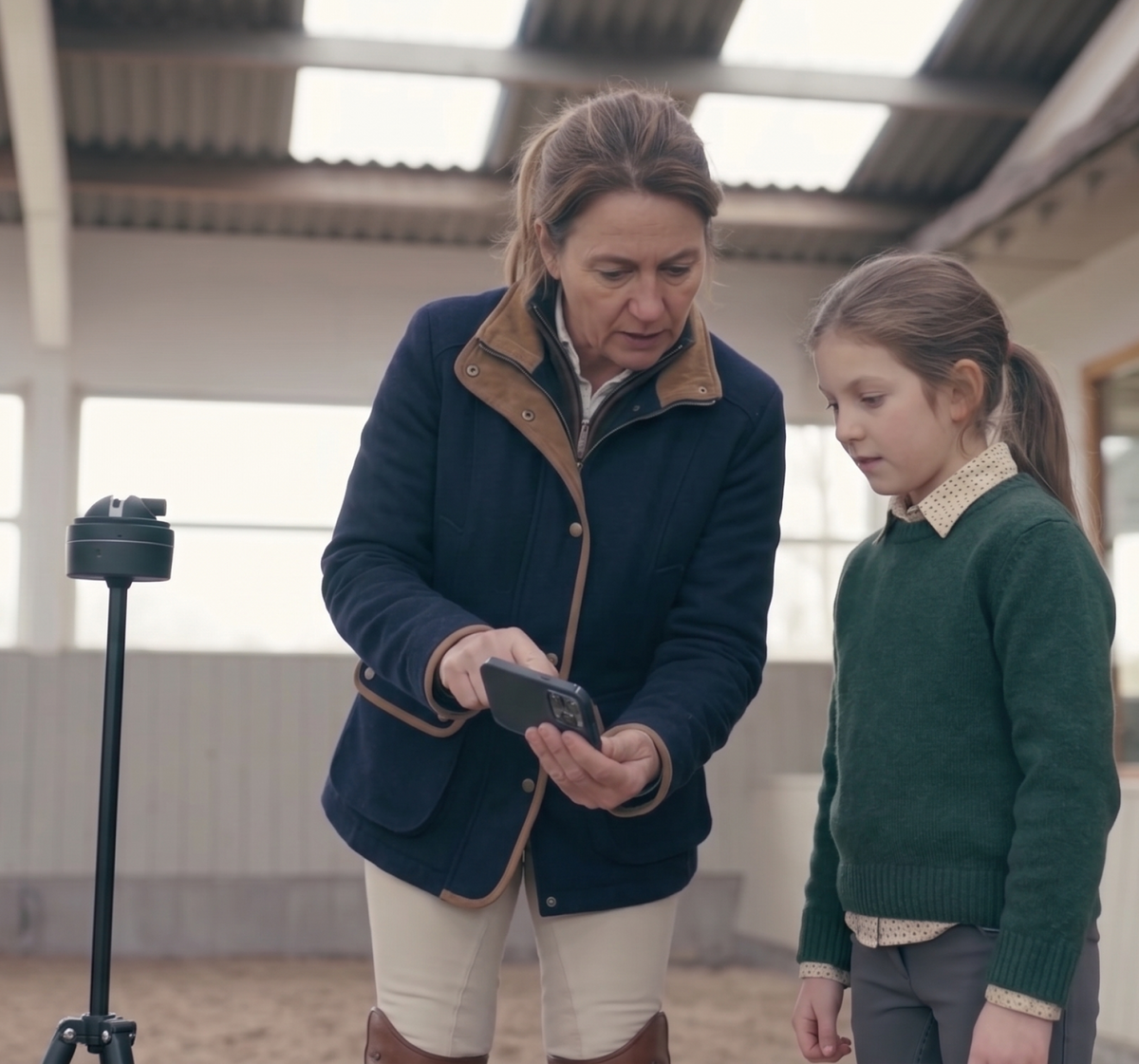Trainer and young rider reviewing a lesson video with Pivo at the barn